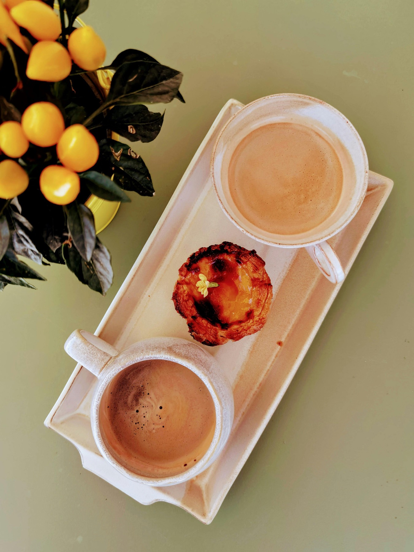 Coffee drinks and pastries arranged on a cafe tray in warm morning light