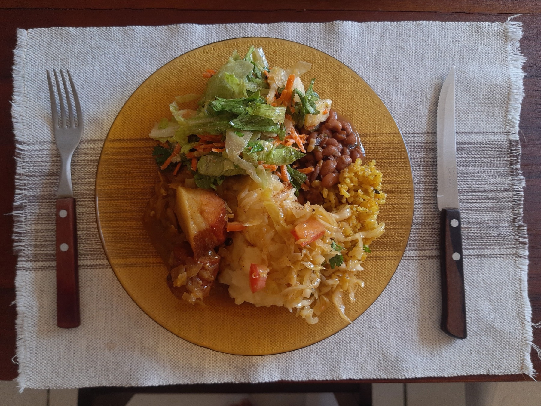 Buffet lunch plate with rice beans vegetables salad and roasted meat arranged on a white plate