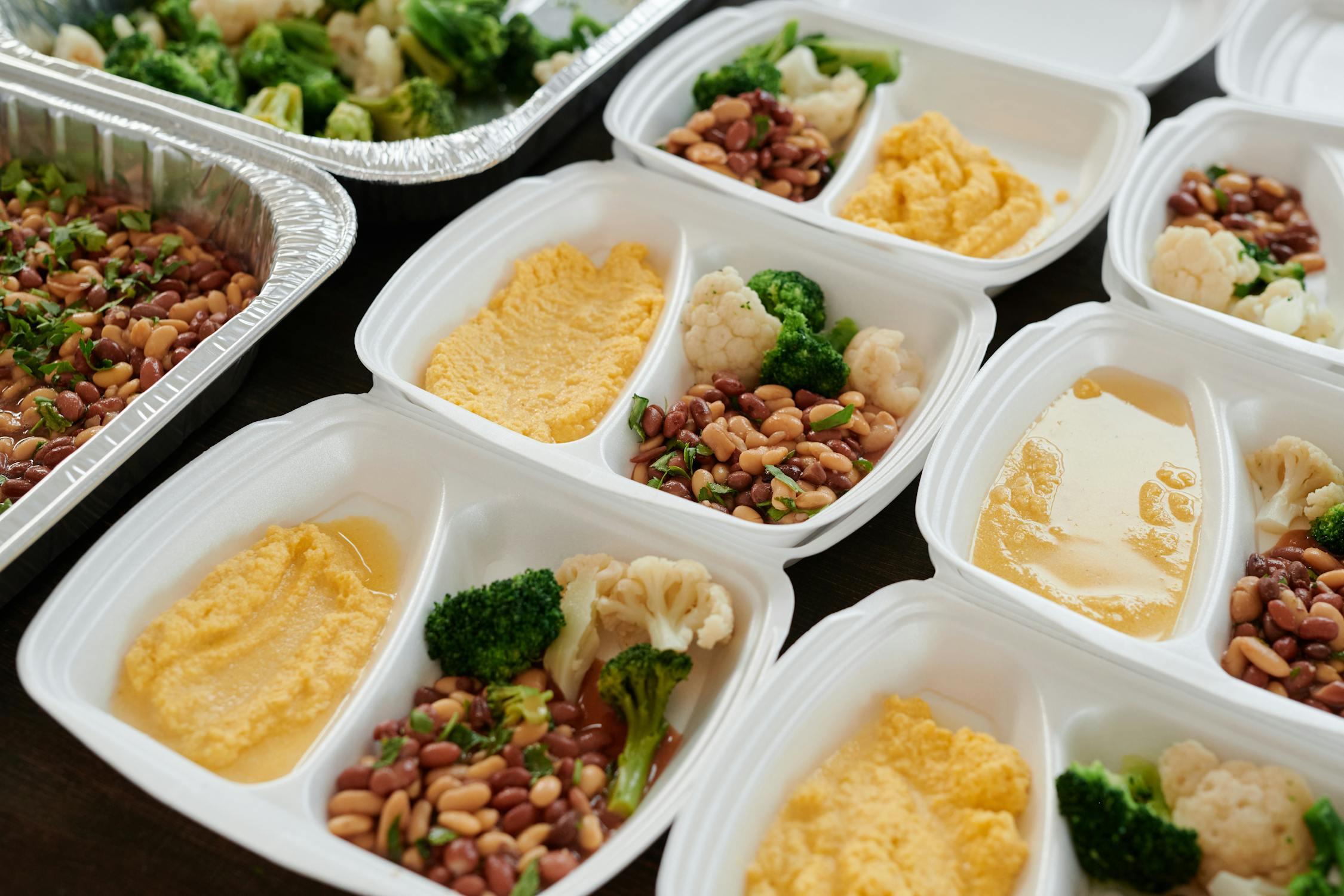 Several meal prep containers filled with vegetables beans and prepared sides on a counter